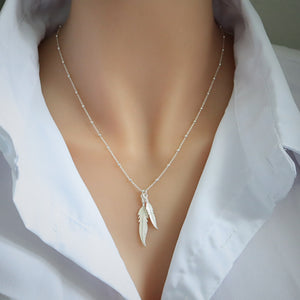 Silver feather necklace on a mannequin with a white shirt