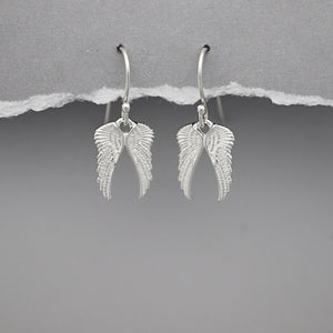 Silver angel wing earrings on a gray background