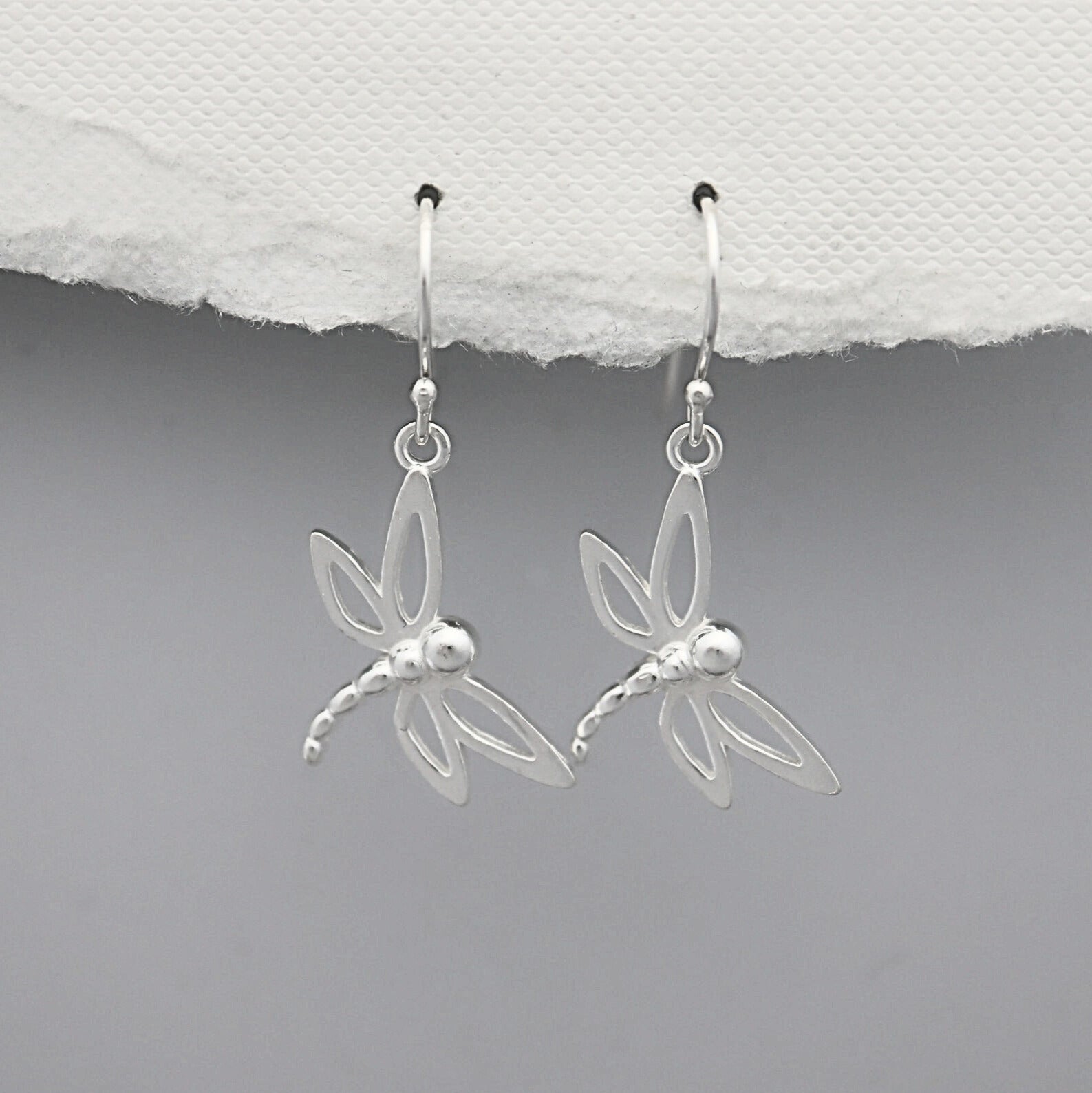 Silver dragonfly earrings on a white and gray background