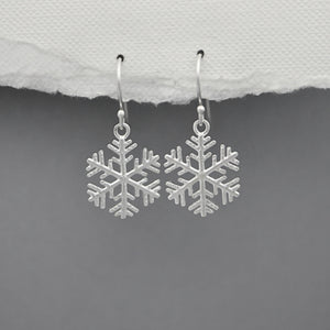 Silver snowflake earrings on a gray background